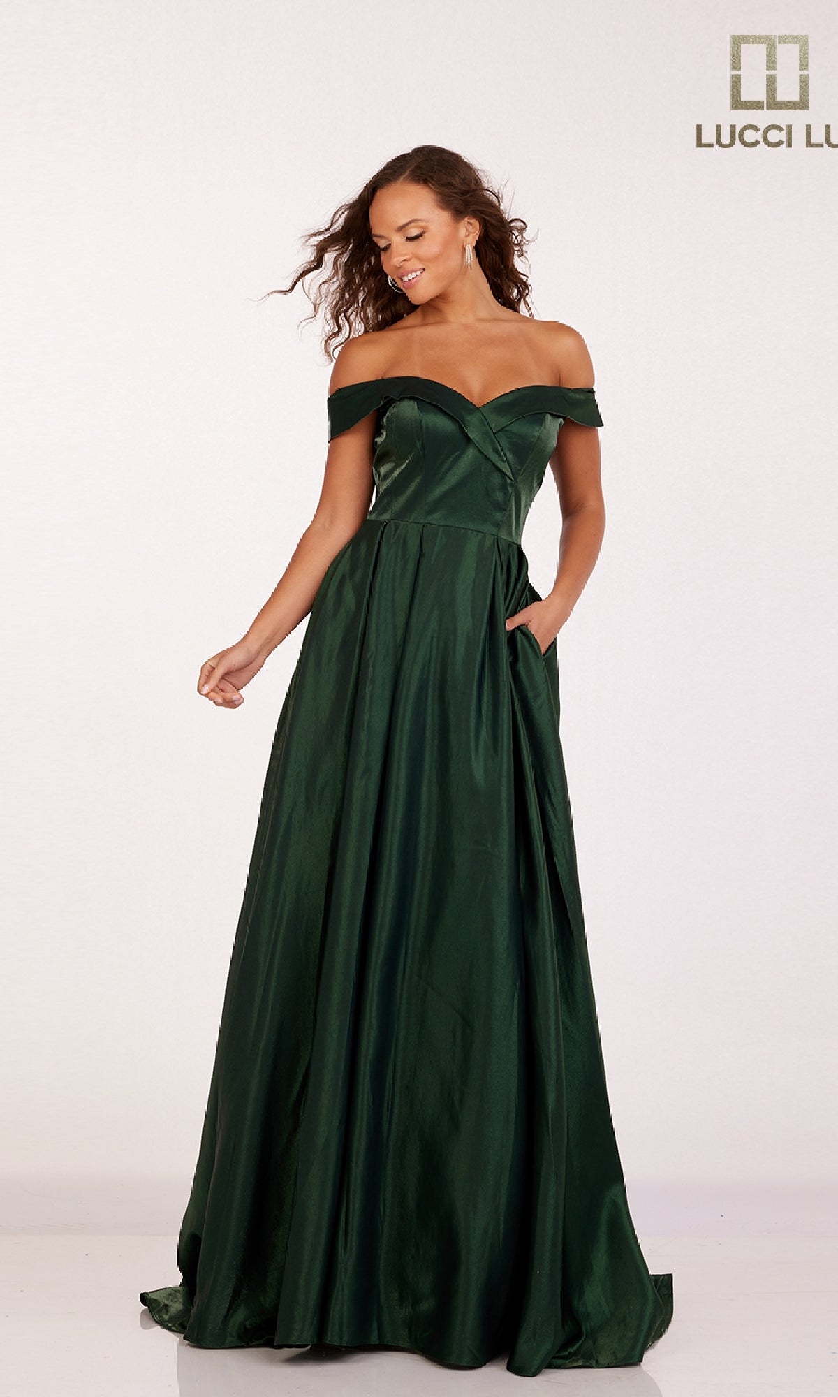 A woman in the Lucci Lu 28063 off-the-shoulder, floor-length dark green satin prom dress stands against a plain background with the Lucci Lu logo in the top right corner.